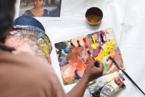 Afrikanischer männlicher Maler bei der Arbeit beim Malen von Porträt auf Leinwand im Kunstatelier. Kreation und Inspiration im Malatelier eines Künstlers. — Stockfoto