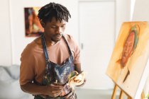 Pittore afroamericano di sesso maschile al lavoro ritratto su tela in studio d'arte. creazione e ispirazione in uno studio di pittura artisti. — Foto stock