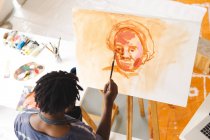 African american male painter at work painting portrait on canvas in art studio. creation and inspiration at an artists painting studio. — Stock Photo