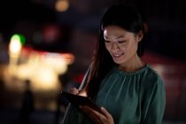 Donna d'affari asiatica che lavora di notte utilizzando tablet. lavorare fino a tardi negli affari in un ufficio moderno. — Foto stock