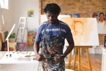 Pintor afroamericano en el trabajo con delantal en el estudio de arte. creación e inspiración en un estudio de pintura de artistas. - foto de stock