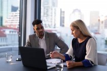 Zwei unterschiedliche männliche und weibliche Geschäftskollegen, die sich unterhalten und Laptop benutzen. Arbeit in einem modernen Büro. — Stockfoto