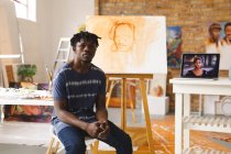 Porträt eines afrikanisch-amerikanischen Malers bei der Arbeit vor der Kamera im Kunstatelier. Kreation und Inspiration im Malatelier eines Künstlers. — Stockfoto