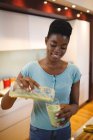 Femme afro-américaine souriante dans la cuisine préparant une boisson santé. mode de vie domestique, profiter du temps libre à la maison. — Photo de stock