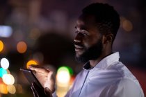 Empresário afro-americano trabalhando à noite usando smartphone. trabalhando até tarde em negócios em um escritório moderno. — Fotografia de Stock