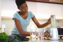 Femme afro-américaine en cuisine préparant une boisson santé. mode de vie domestique, profiter du temps libre à la maison. — Photo de stock