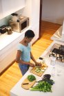 Mujer afroamericana en cocina picando verduras y frutas. estilo de vida doméstico, disfrutando del tiempo libre en casa. - foto de stock