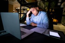 Gemischter Geschäftsmann, der nachts arbeitet, am Schreibtisch sitzt und Laptop benutzt. spät arbeiten in einem modernen Büro. — Stockfoto