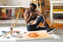 Pittore afroamericano di sesso maschile al lavoro ritratto su tela in studio d'arte. creazione e ispirazione in uno studio di pittura artisti. — Foto stock