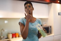 Mulher afro-americana na cozinha preparando bebida saudável. estilo de vida doméstico, desfrutando de tempo de lazer em casa. — Fotografia de Stock