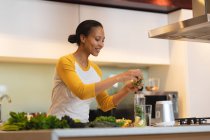 Усміхнена змішана жінка на кухні готує здоровий напій. домашній спосіб життя, насолоджуючись дозвіллям вдома . — стокове фото