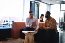 Dois colegas de negócios diferentes do sexo masculino usando tablet e conversando. trabalhando em negócios em um escritório moderno. — Fotografia de Stock