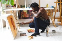 Pintor afroamericano en el trabajo pintando retrato sobre lienzo en el estudio de arte. creación e inspiración en un estudio de pintura de artistas. - foto de stock