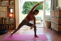 Kaukasische Frau im Wohnzimmer, praktiziert Yoga, dehnt sich. häuslicher Lebensstil, Freizeit zu Hause genießen. — Stockfoto