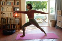 Kaukasische Frau im Wohnzimmer, praktiziert Yoga, dehnt sich. häuslicher Lebensstil, Freizeit zu Hause genießen. — Stockfoto