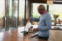 Homem americano africano sênior na cozinha moderna fazendo um café. estilo de vida aposentadoria, passar o tempo sozinho em casa. — Fotografia de Stock