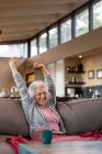 Felice donna caucasica anziani seduti sul divano e utilizzando tablet nel moderno soggiorno. stile di vita di pensione, trascorrere del tempo da solo a casa. — Foto stock