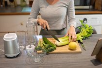 Mulher na cozinha, preparando bebida saudável, cortando legumes. estilo de vida doméstico, desfrutando de tempo de lazer em casa. — Fotografia de Stock