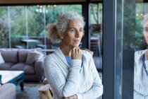 Mulher caucasiana sênior pensativa na sala de estar, olhando para a janela. estilo de vida aposentadoria, passar o tempo sozinho em casa. — Fotografia de Stock