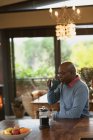 Homem americano africano sênior situado na cozinha moderna e beber café. estilo de vida aposentadoria, passar o tempo sozinho em casa. — Fotografia de Stock