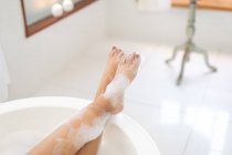 Low section of woman in bathroom relaxing in bath. domestic lifestyle, enjoying self care leisure time at home. — Stock Photo