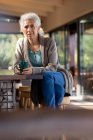 Rilassante donna caucasica anziana in cucina seduta a bere caffe '. stile di vita di pensione, trascorrere del tempo da solo a casa. — Foto stock