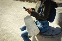 Жінка сидить і використовує смартфон у сонячний день на узбережжі. здоровий спосіб життя, насолоджуючись дозвіллям на відкритому повітрі . — стокове фото