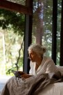 Senior caucasian woman lying on the bad and using tablet. retirement lifestyle, spending time alone at home. — Stock Photo