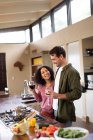 Feliz casal diversificado na cozinha preparando comida juntos bebendo vinho. passar o tempo fora em casa no apartamento moderno. — Fotografia de Stock