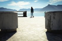 Gara mista donna skateboard nella giornata di sole al mare. stile di vita sano, godendo del tempo libero all'aperto. — Foto stock