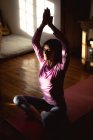 Mujer de raza mixta practicando yoga en el salón soleado. estilo de vida saludable, disfrutando del tiempo libre en casa. - foto de stock