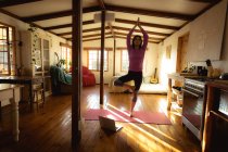 Donna razza mista praticare yoga in soggiorno soleggiato. stile di vita sano, godendo del tempo libero a casa. — Foto stock