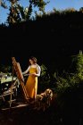 Donna caucasica in giardino soleggiato con il suo cane da compagnia, dipinto su tela. stile di vita domestico, godendo del tempo libero a casa. — Foto stock