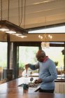 Старший африканский американец на современной кухне делает кофе. пенсионного образа жизни, проводить время в одиночестве на дому. — стоковое фото