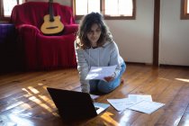 Змішана расова жінка працює дистанційно, використовуючи ноутбук у сонячній вітальні. здоровий спосіб життя, віддалена робота з дому . — стокове фото