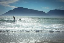 Mixed-Rennläuferin beim Surfen im Meer an einem sonnigen Tag. gesunder Lebensstil, Freizeit im Freien genießen. — Stockfoto