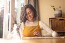 Smiling caucasian woman in living room, sitting at table painting. domestic lifestyle, enjoying leisure time at home. — Stock Photo