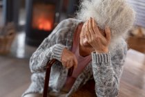 Ragionevole donna caucasica anziana seduta in cucina appoggiata al bastone da passeggio. stile di vita di pensione, trascorrere del tempo da solo a casa. — Foto stock
