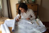 Kaukasische Architektin im Wohnzimmer, am Tisch sitzend, Pläne zeichnend. häuslicher Lebensstil, Fernarbeit von zu Hause aus. — Stockfoto