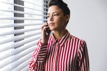 Thoughtful caucasian female business creative looking through window and using smartphone. independent creative business people working at a modern office. — Stock Photo