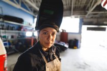 Meccanico misto corsa femminile auto indossando tuta e maschera di saldatura, guardando la fotocamera. proprietario indipendente presso il garage di assistenza auto. — Foto stock