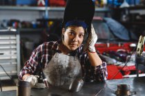Mixed race female car mechanic welding car part in workshop. independent business owner at car servicing garage. — Stock Photo