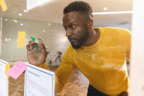 Sério Africano americano masculino negócios criativo brainstorming e escrever notas memorando na parede de vidro. empresários criativos independentes que trabalham em um escritório moderno. — Fotografia de Stock