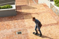 Serious caucasian male business creative arriving on skateboard outside workplace. independent creative business people working at a modern office. — Stock Photo