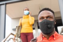 Ernste afrikanisch-amerikanische Kreativ-Kollegen mit Gesichtsmasken gehen die Treppe hinunter. unabhängige kreative Geschäftsleute in einem modernen Büro bei Coronavirus covid 19 Pandemie. — Stockfoto