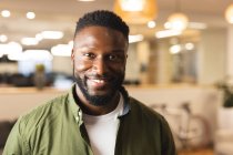 Retrato de sorrir afro-americano macho criativo olhando para a câmera. trabalhando em negócios criativos em um escritório moderno. — Fotografia de Stock