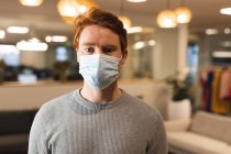 Portrait of caucasian male creative wearing face mask at work, looking to camera. working in creative business at a modern office during coronavirus pandemic. — Stock Photo