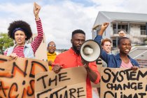 Hombre afroamericano usando megáfono y sosteniendo pancarta en una marcha de protesta. manifestantes por la igualdad de derechos y justicia en marcha. - foto de stock