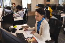 Gemischte Rasse weibliche Kreative bei der Arbeit, am Schreibtisch sitzend, am Computer. Arbeit im kreativen Geschäft in einem modernen Büro. — Stockfoto