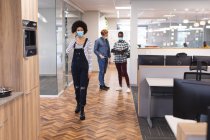 Коллеги мужского и женского пола носят маски, работают вместе. работа в творческом бизнесе в современном офисе во время пандемии коронавируса. — стоковое фото